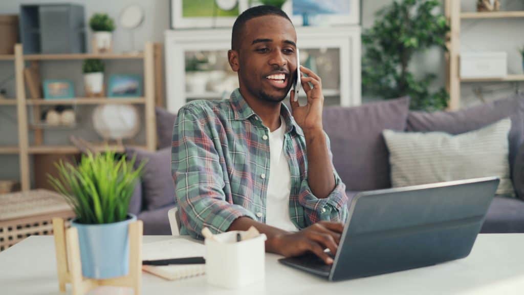 Man on phone with laptop at home, promoting health education services.
